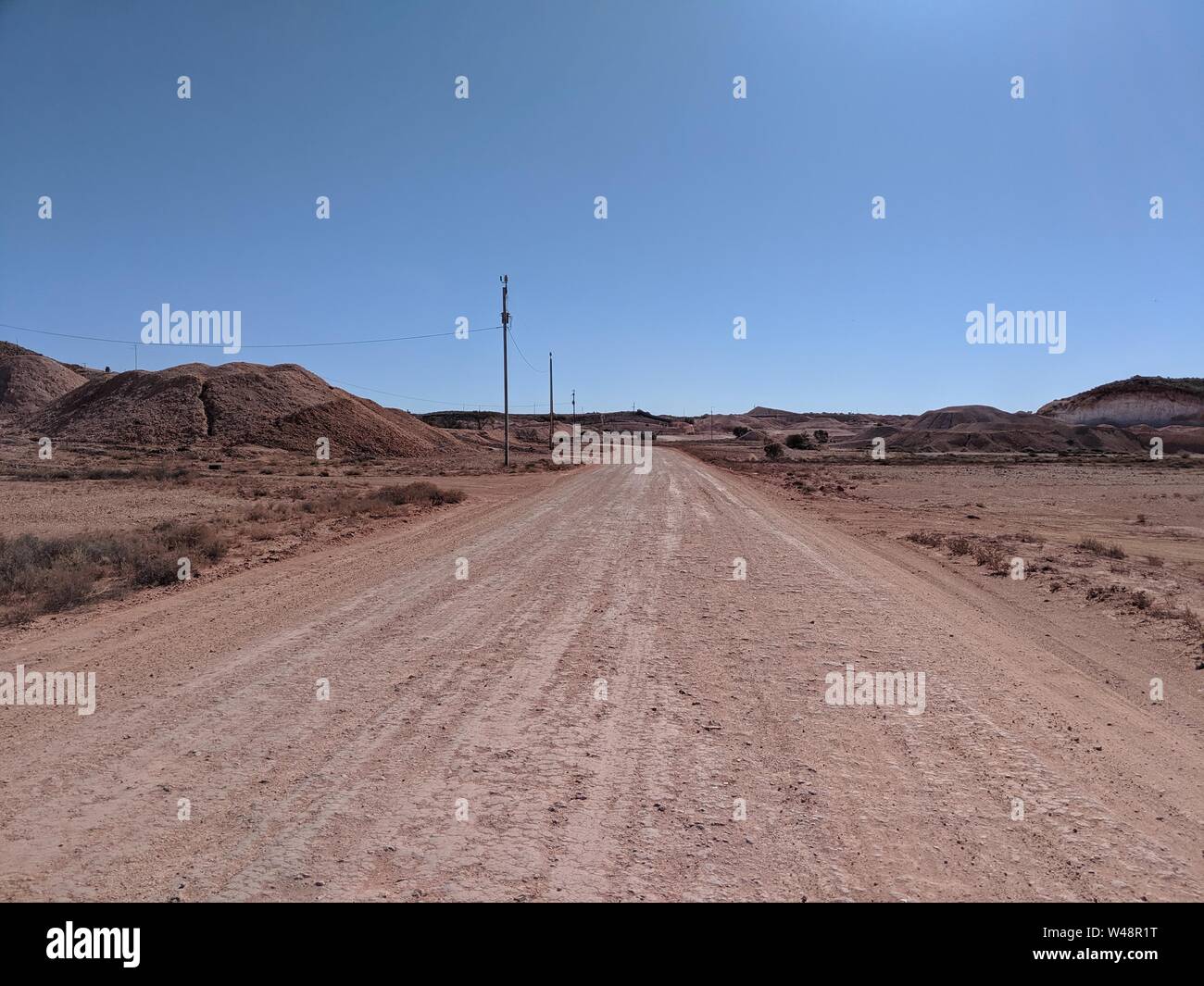 Dry dusty road through the outback, Coober Pedy, red centre of Australia Stock Photo