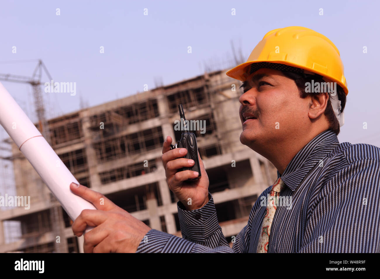 Architect holding blueprint at construction site Stock Photo - Alamy