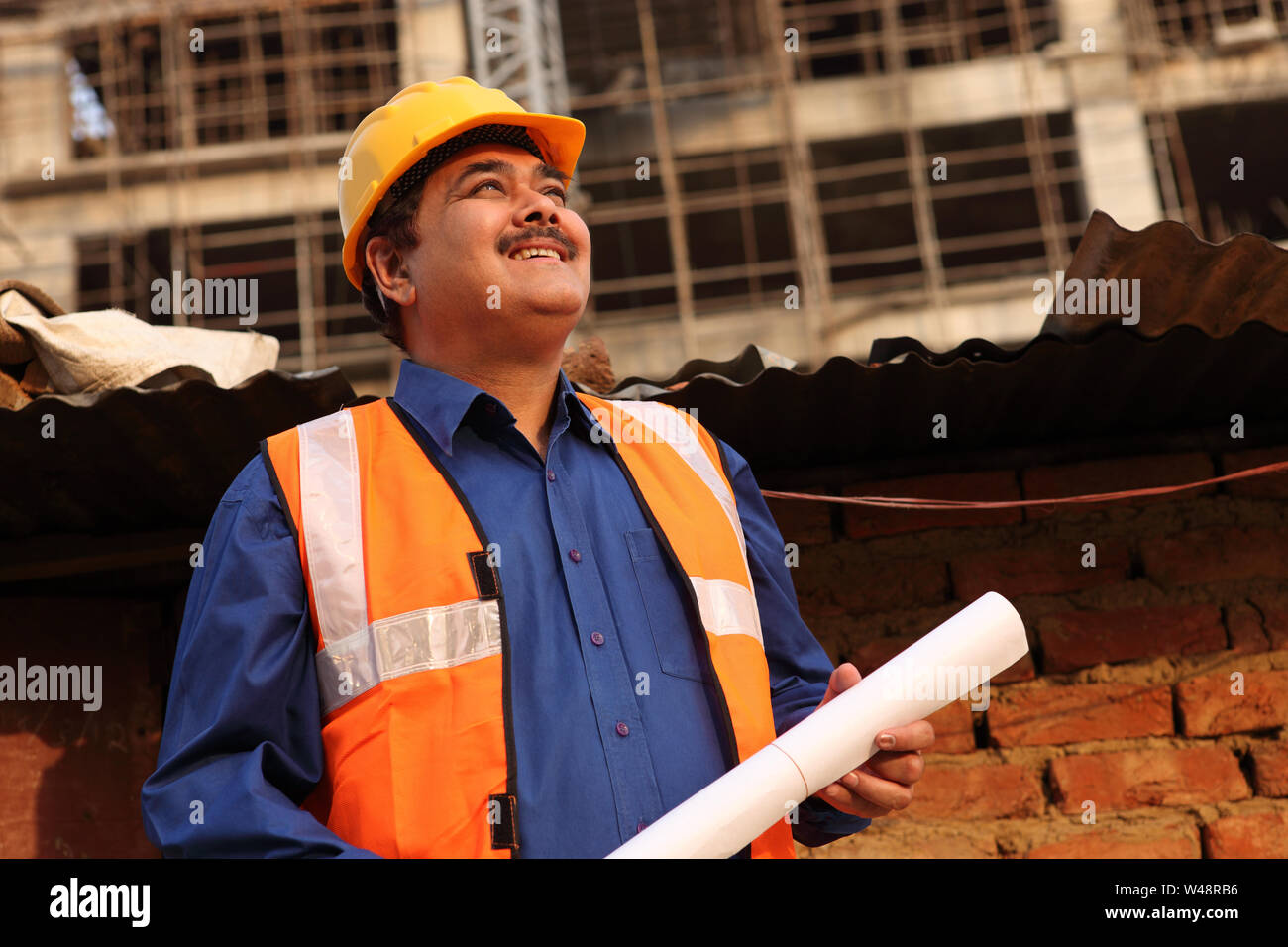 Architect holding blueprint at construction site Stock Photo - Alamy