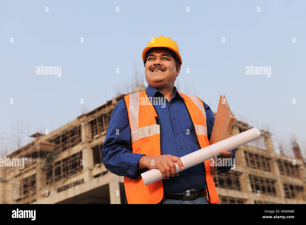 Architect holding blueprint at construction site Stock Photo - Alamy