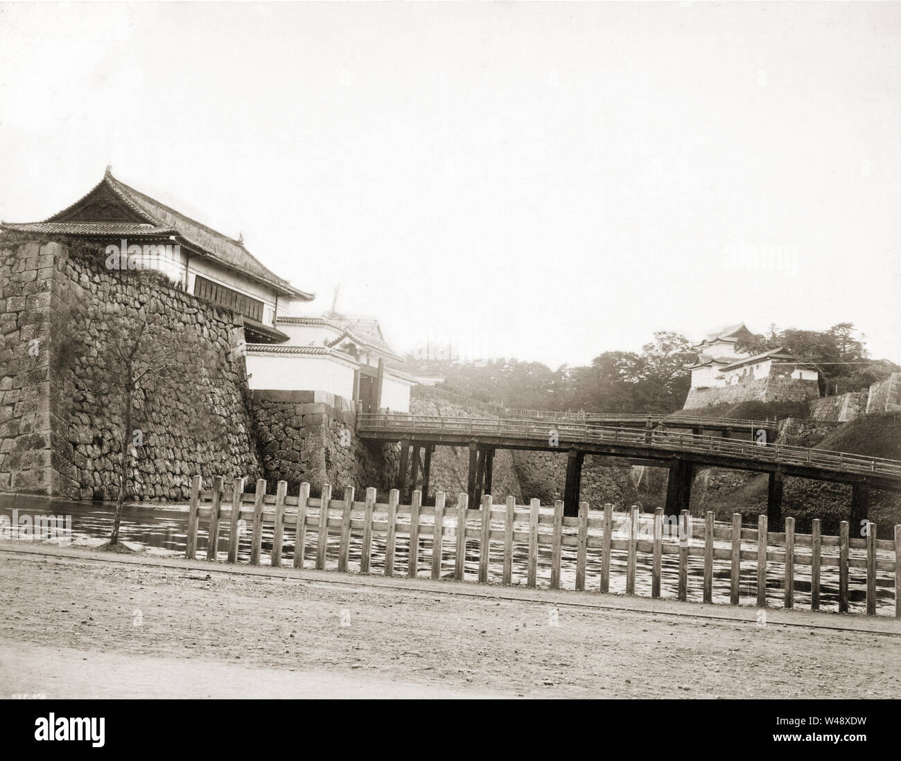 [ 1870s Japan - Imperial Palace, Tokyo ] —   Nijubashi at the Imperial Palace in Tokyo. The two wooden bridges on this image were known as Nijubashi. In 1887 (Meiji 20) and 1888, they were replaced by a stone, and an iron bridge. Notice the dilapidated state of the building at the back.  19th century vintage albumen photograph. Stock Photo
