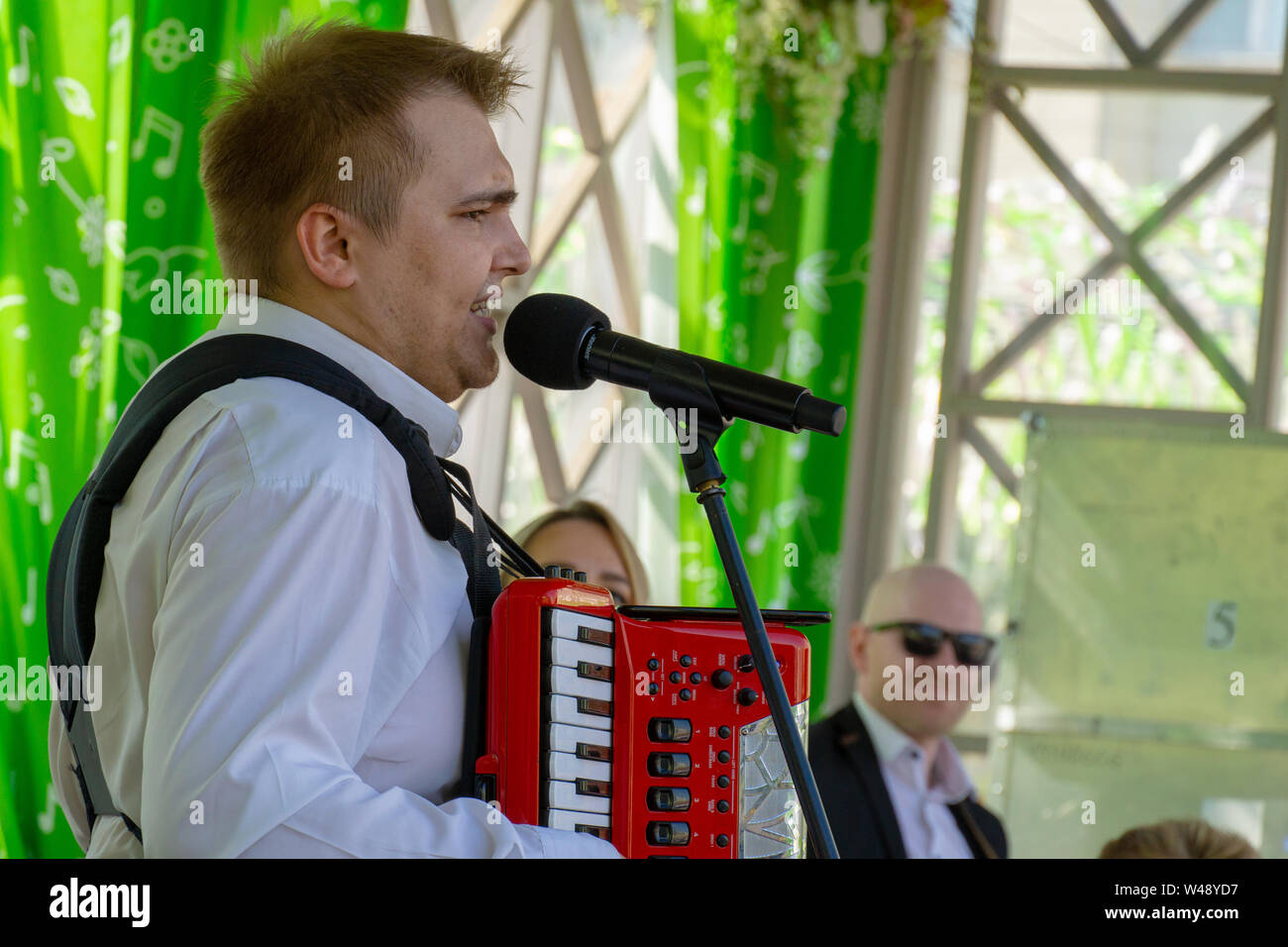 MOSCOW, RUSSIA - MAY 9, 2019: Man in white shirt playing accordion and singing Stock Photo