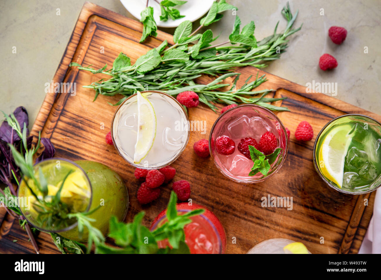 Summer soft drinks, a set of lemonades. Lemonades in jugs on the table, the ingredients of which they are made are arranged around. Stock Photo