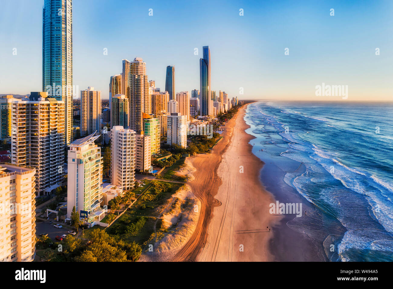Waterfront of Surfers Paradise city high-rise towers growing from wide long sandy beach against open wild waves of Pacific ocean on Australian Gold Co Stock Photo