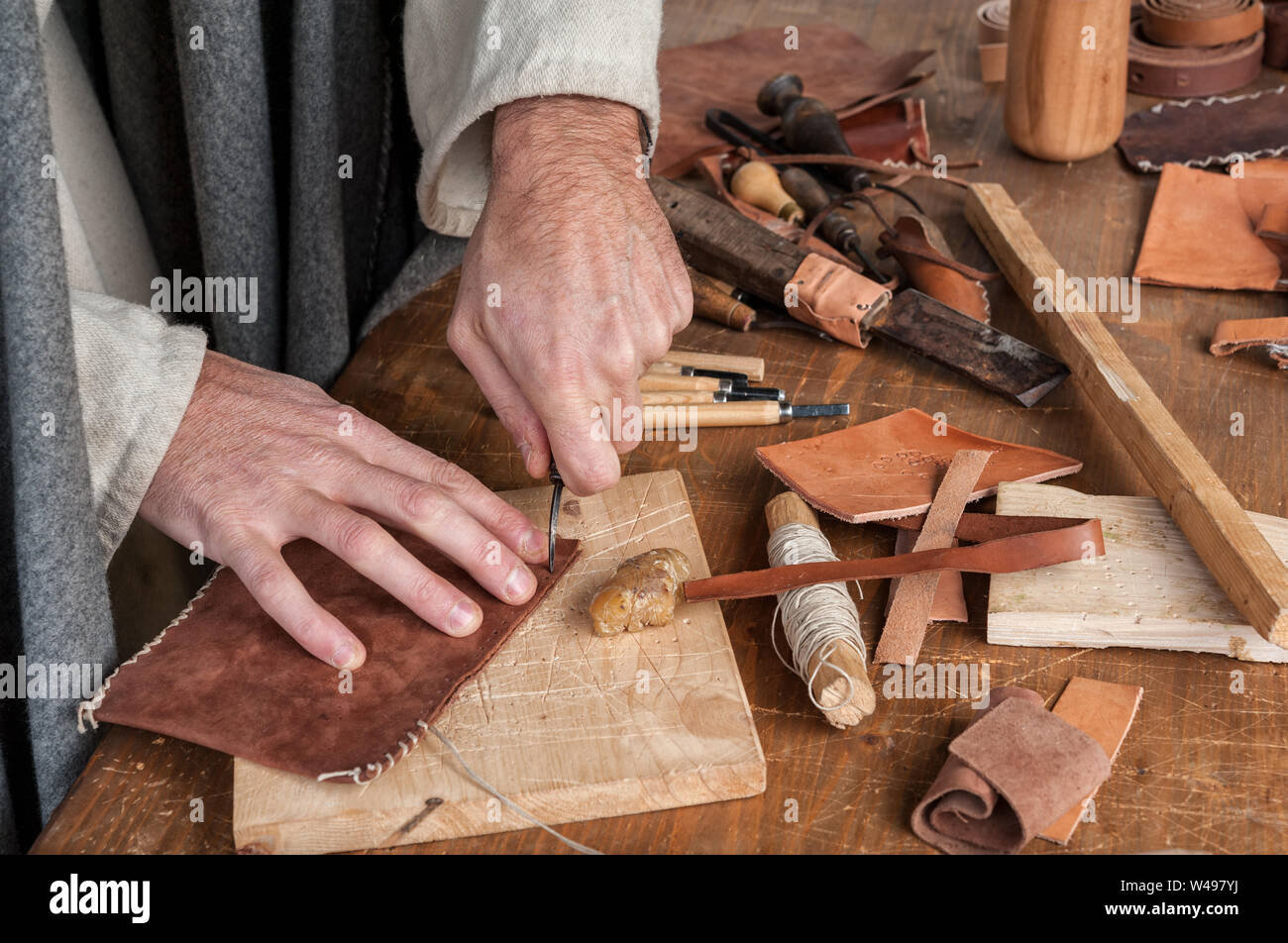 Master craftsman works leather on his workbench Stock Photo
