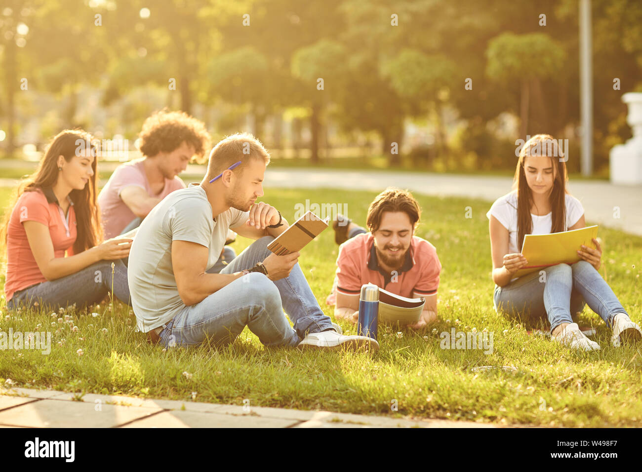 A group of students studying books sitting in a city park. Stock Photo