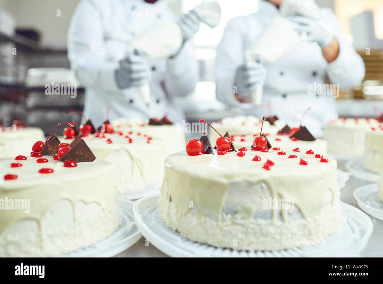 Red cherry on white cake on a table with cakes Stock Photo