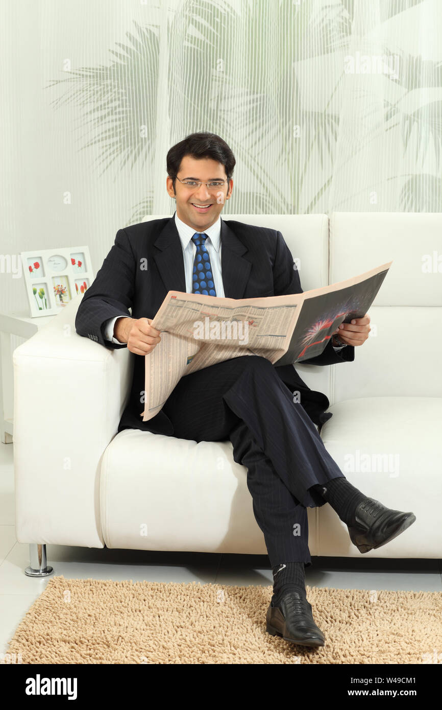 Businessman reading a newspaper and smiling Stock Photo - Alamy