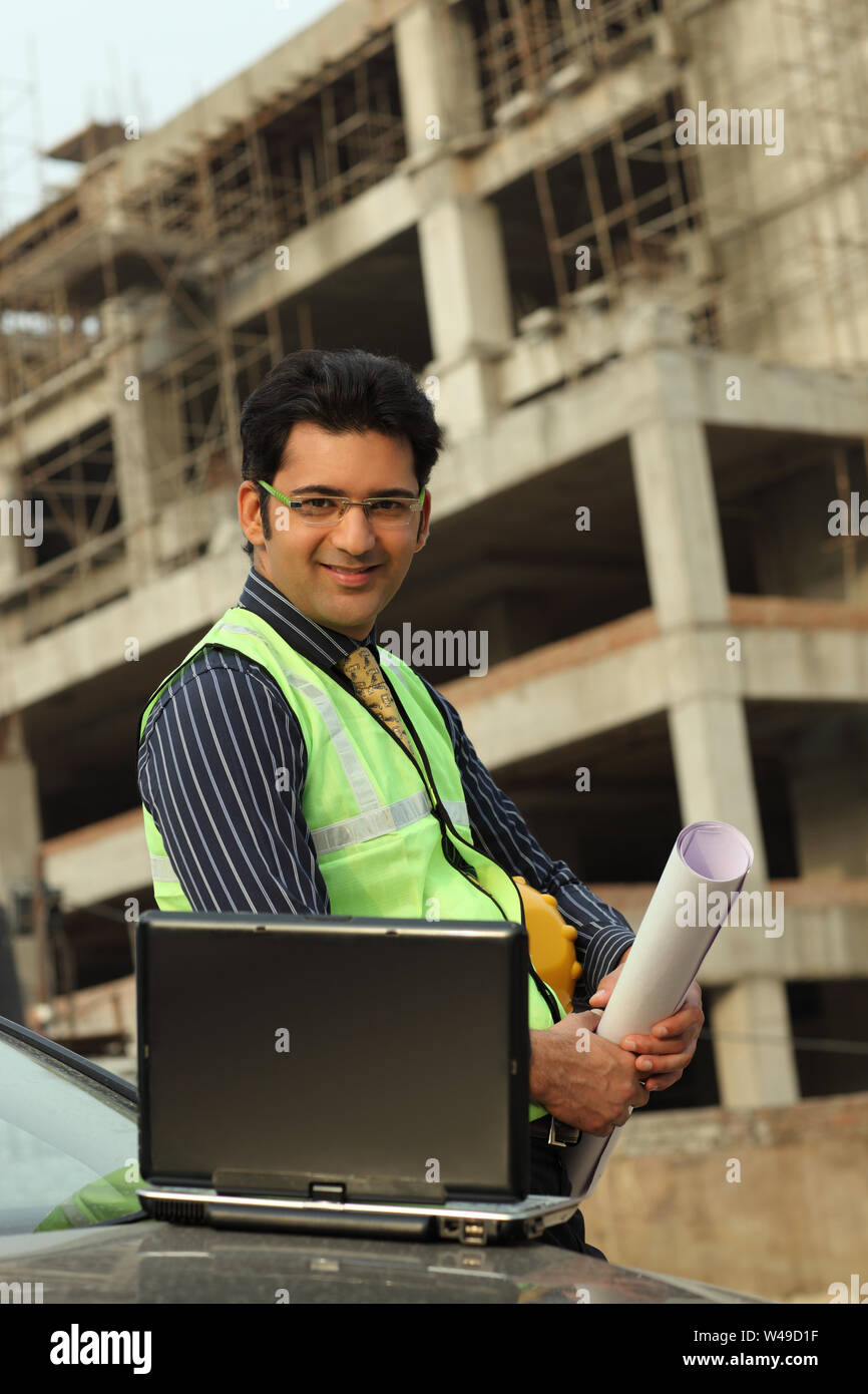 Architect holding blueprint at a construction site Stock Photo - Alamy