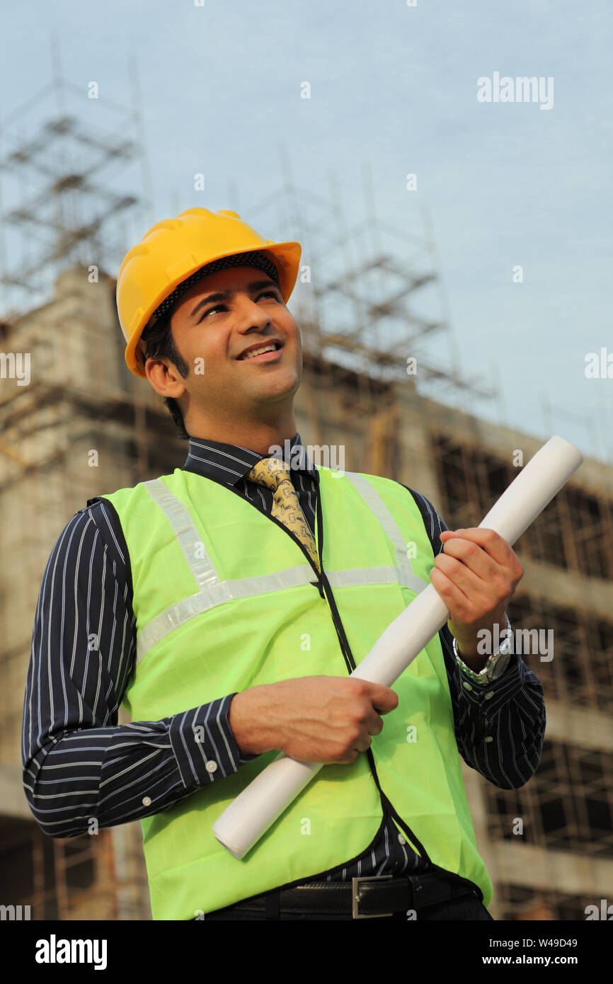 Architect holding blueprint at a construction site Stock Photo - Alamy