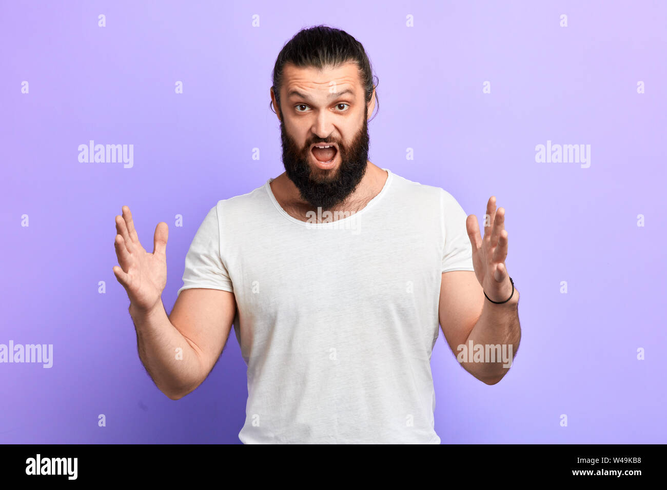 angry nervous frustrated man with hand raised open mouth shouting at somebody, isolated on blue background. Negative emotion, facial expression feelin Stock Photo