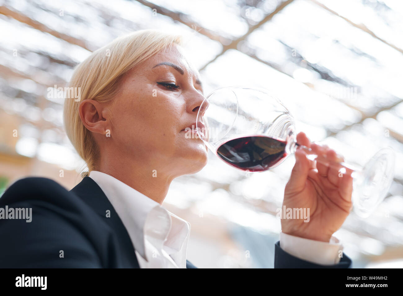 Serious winery expert holding bokal of red wine evaluating its smell