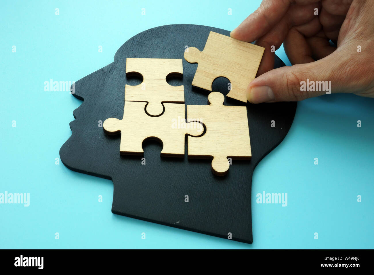 Problem solving concept. Hand puts piece of puzzle on head shape. Stock Photo