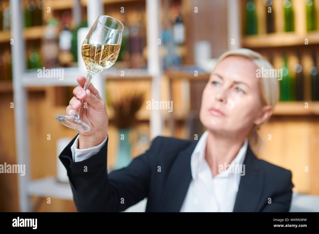 Female hand holding bokal woth white wine while examining its color Stock Photo