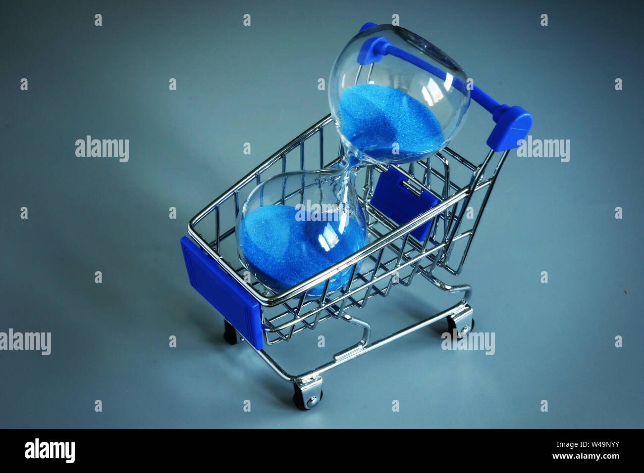 Buying some time for yourself. Shopping cart and sand clock. Stock Photo