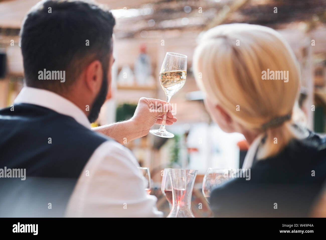 Two professional cavists studying characteristics of wine sample in flute Stock Photo