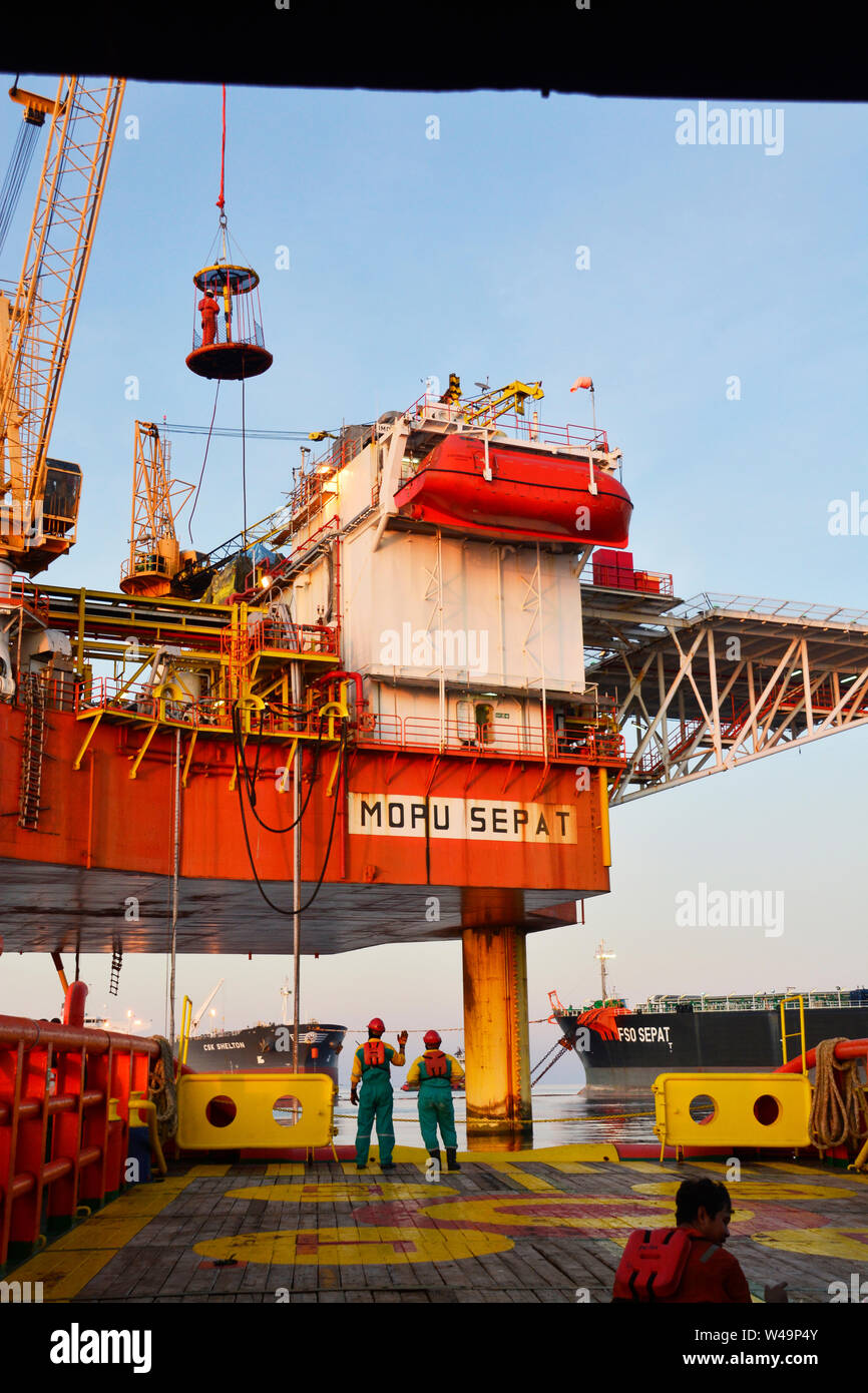 ship crew working on deck during transfer oil platform personal to vessel by safety basket operate by crane operator Stock Photo