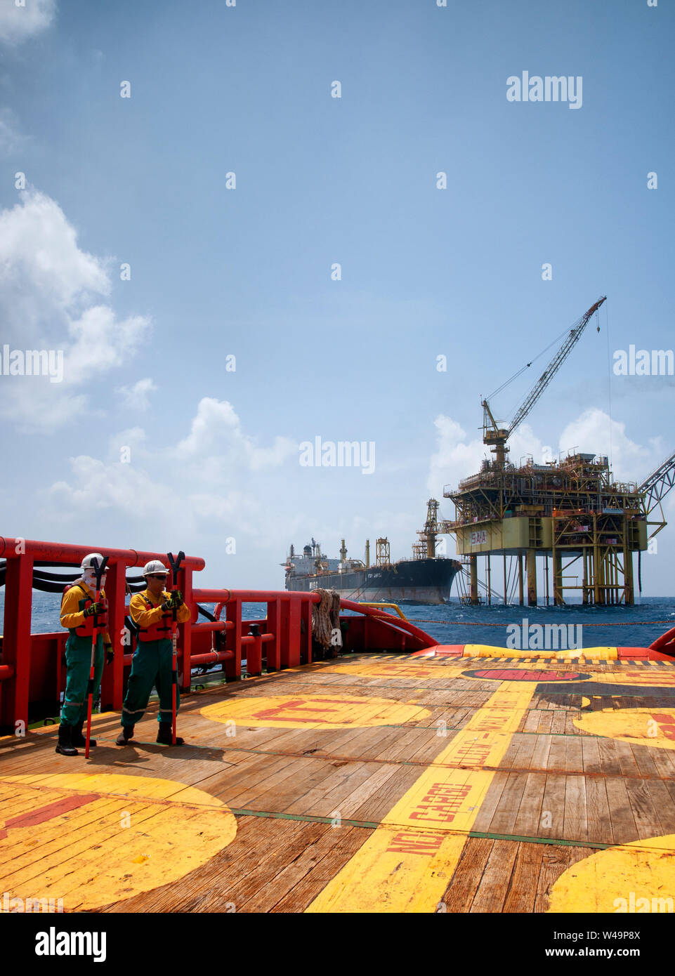 ship crew stand by on deck to received cargo lift to the boat by crane operator at oil platform Stock Photo