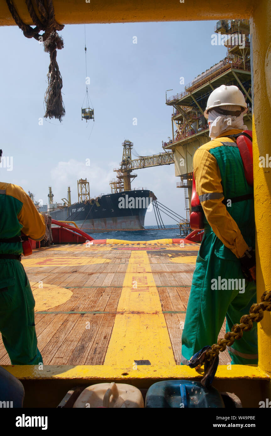 ship-crew-stand-by-on-deck-to-received-cargo-lift-to-the-boat-by-crane-operator-at-oil-platform