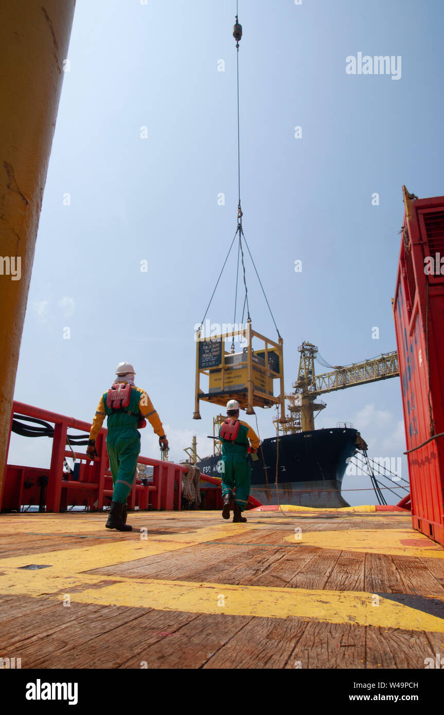 ship crew stand by on deck to received cargo lift to the boat by crane operator at oil platform Stock Photo