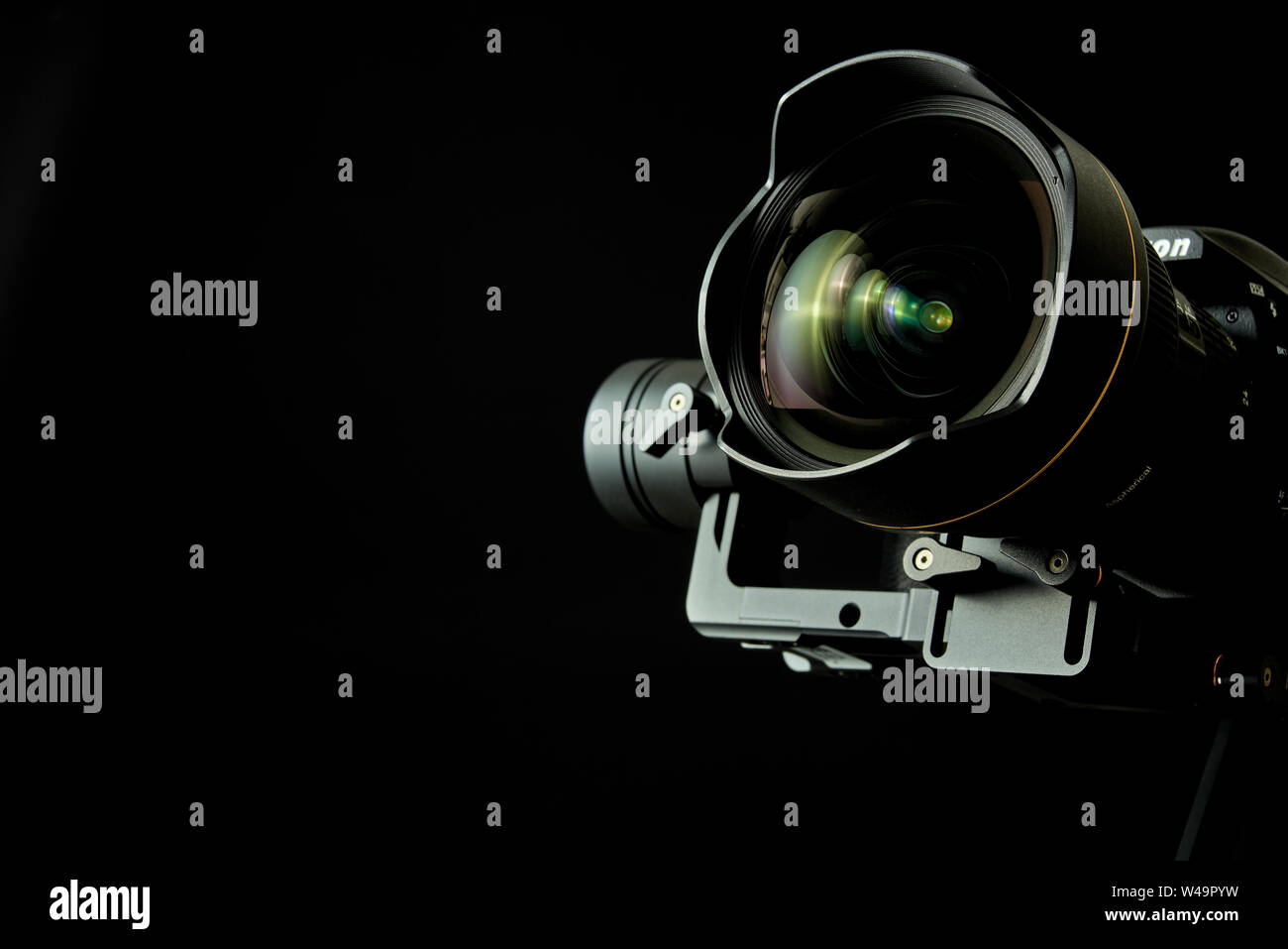 Close-up of wide angle lens in a dsl camera and gimbal stabilizer, with low-key lighting and a black background Stock Photo
