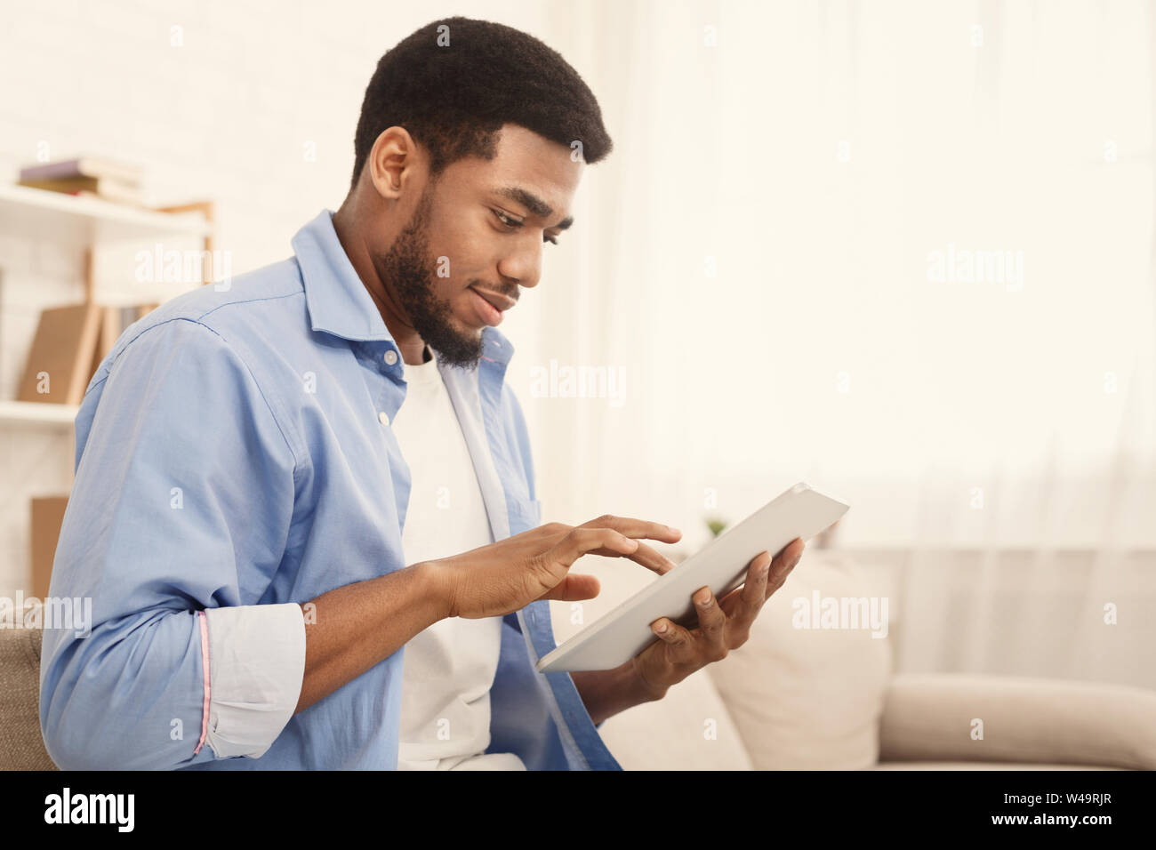 Black man using digital tablet on couch at home Stock Photo