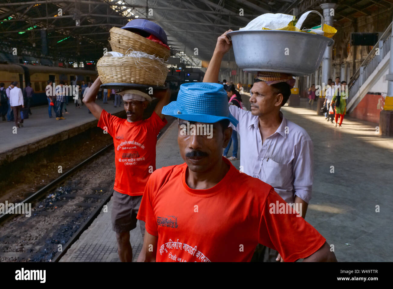 Porters at Chhatrapati Shivaji Maharaj Terminus (CSMT) in Mumbai, India, waiting for a train to deliver their goods from a nearby fish market Stock Photo