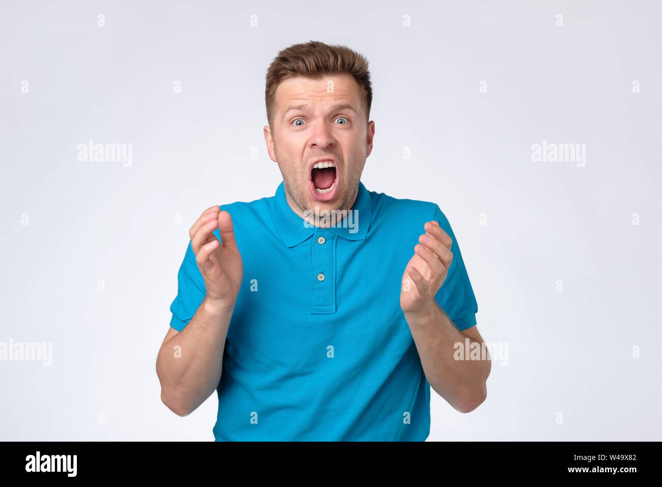 Young european guy in blue shirt shouting Stock Photo