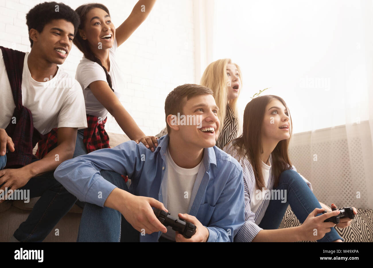 Teen friends playing video games at home Stock Photo