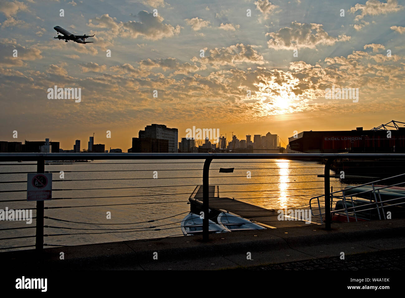 Sunset over the Emirate Royal Docks. Looking west from Connaught Bridge towards central London. An aircraft on final approach th London City Airport Stock Photo