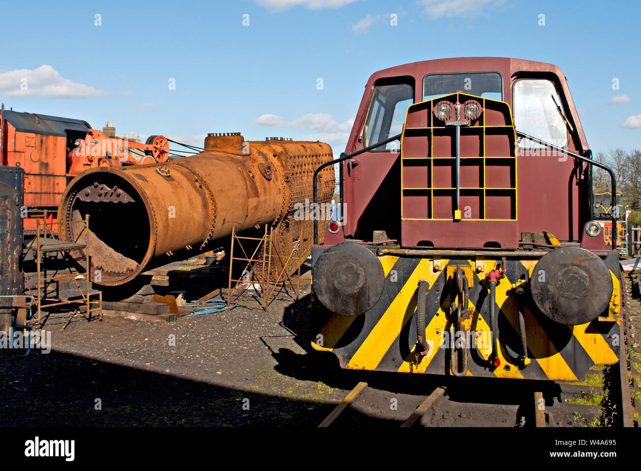 A steam engine boiler in the yard at Wansford on the Nene Valley Railway UK. A vintage shunting loco is on the right Stock Photo