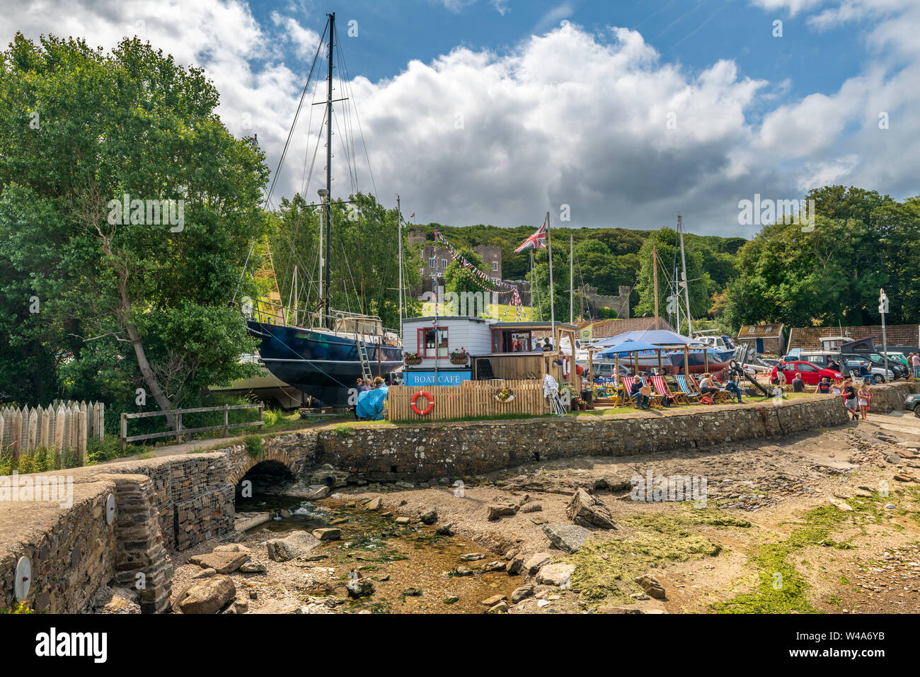 Watermouth Harbour, Berrynarbor, near Ilfracombe, North Devon, England. Sunday 21st July 2019. UK Weather.  Despite the gathering cloud holidaymakers enjoy the long sunny intervals and admire the view over Watermouth Harbour as they take refreshments at the 'Storm in a Teacup cafe'. Credit: Terry Mathews/Alamy Live News Stock Photo
