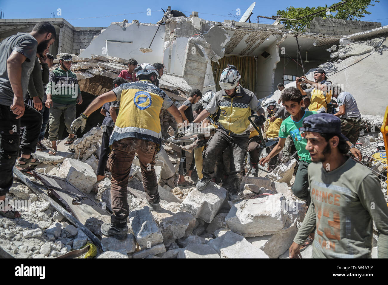 Urm Al Jaws, Syria. 21st July, 2019. Members of the Syrian Civil Defence also known as 'White Helmets' carry a victim after a building collapsed during a reported air strike by pro-regime forces in the town of Urm Al-Jaws in the south of Syria s Idlib Credit: Anas Alkharboutli/dpa/Alamy Live News Stock Photo