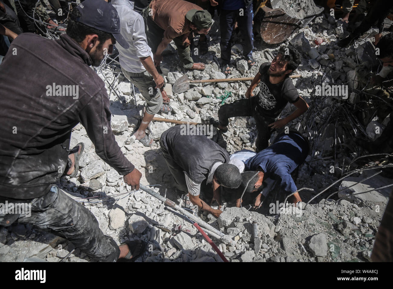Urm Al Jaws, Syria. 21st July, 2019. Syrian civilians search for victims or survivors after a building collapsed during a reported air strike by pro-regime forces in the town of Urm Al-Jaws south of Idlib. Credit: Anas Alkharboutli/dpa/Alamy Live News Stock Photo