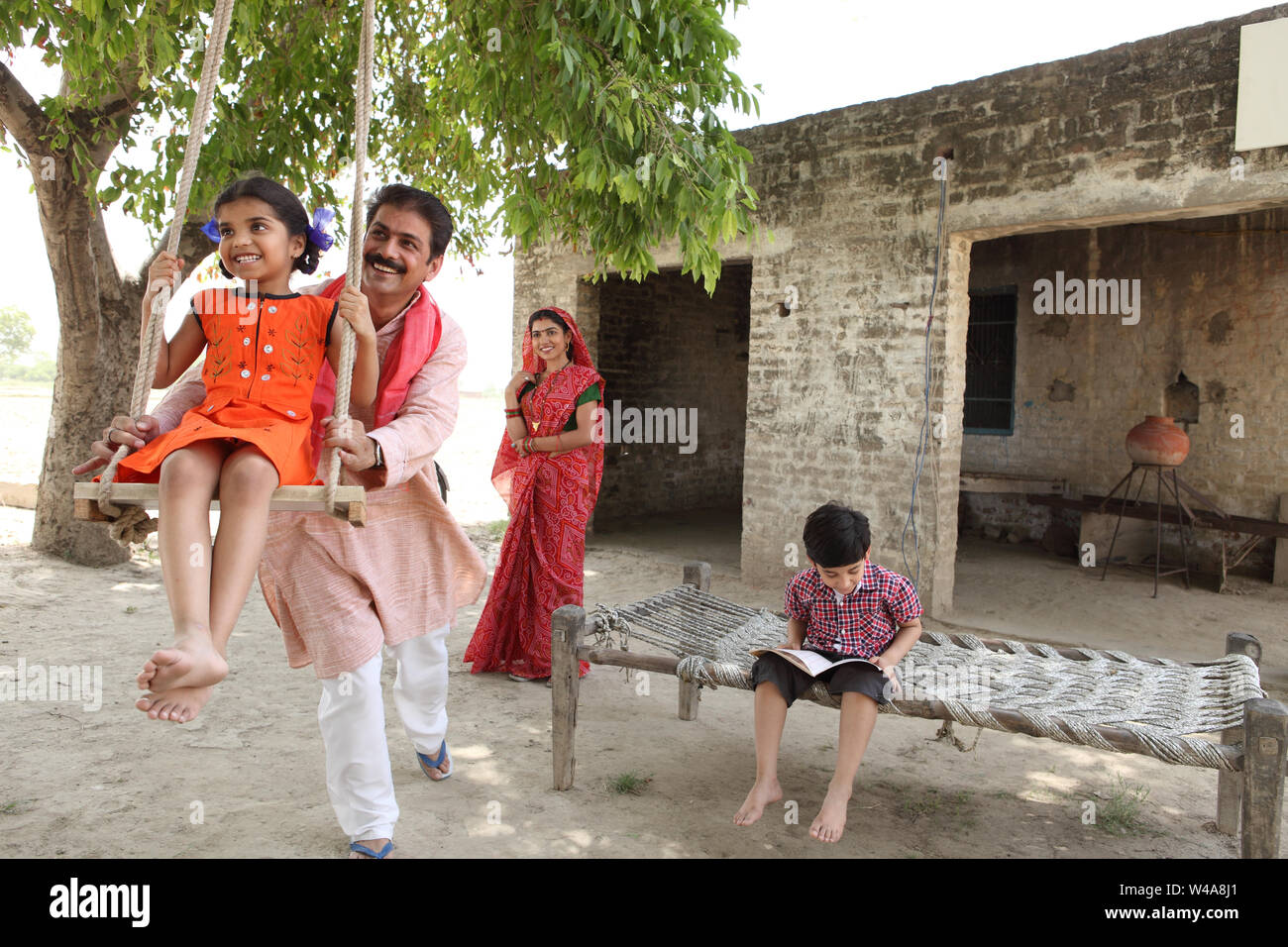 Man pushing his daughter on the swing Stock Photo