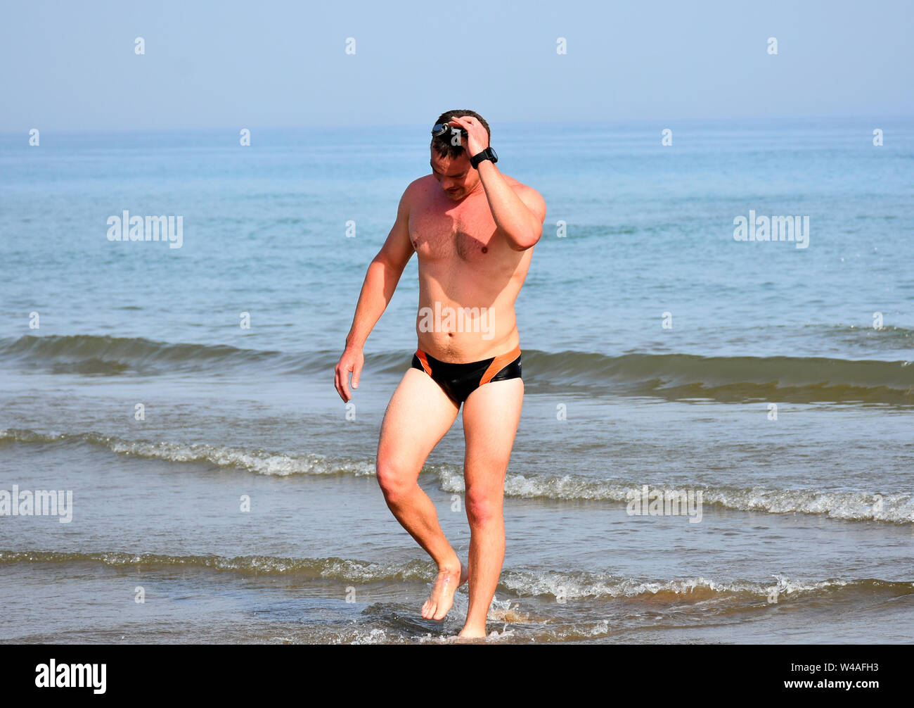 A young European man finishing swimming competition after losing it. The last participant feeling upset. Depressed Stock Photo