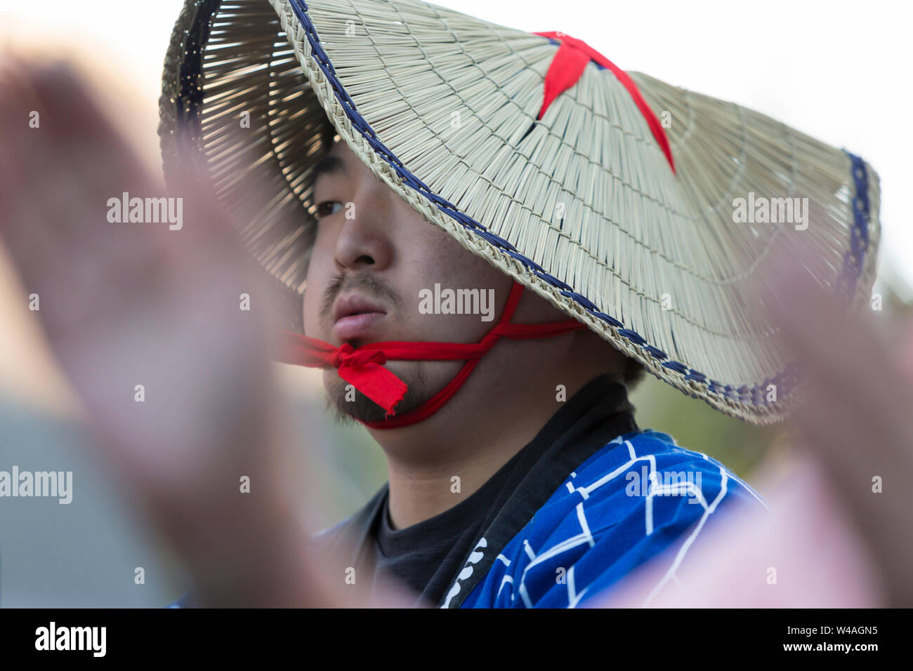A young man wears a traditional amigasa hat during a Bon dance at the 87th annual Bon Odori Festival in Seattle, Washington on July 20, 2019. The lively summer festival features traditional music and folk dance to welcome the spirits of the dead and celebrate the lives of ancestors. Stock Photo