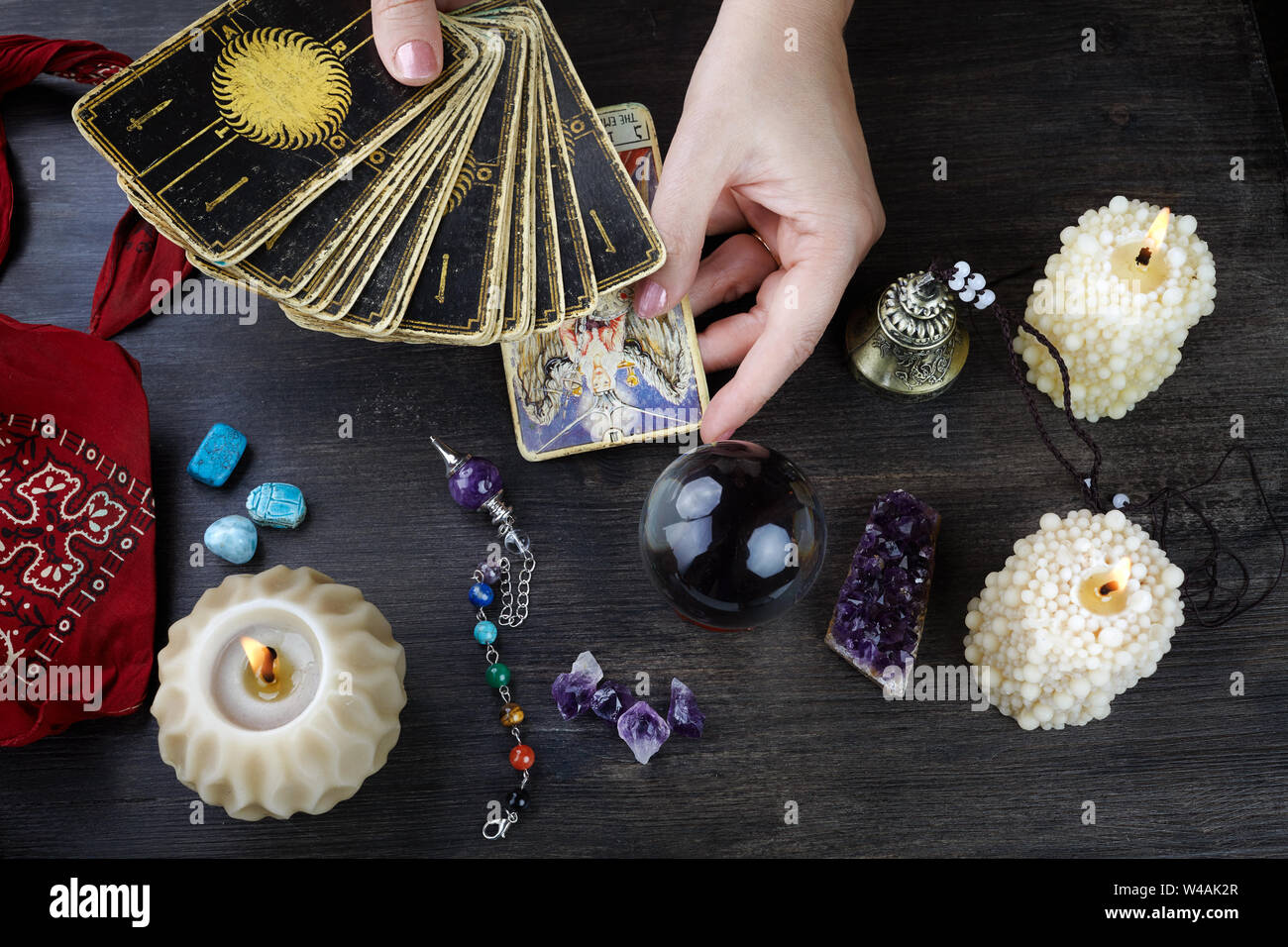 Fortune teller female hands and tarot cards on dark wooden table. Divination concept. Stock Photo