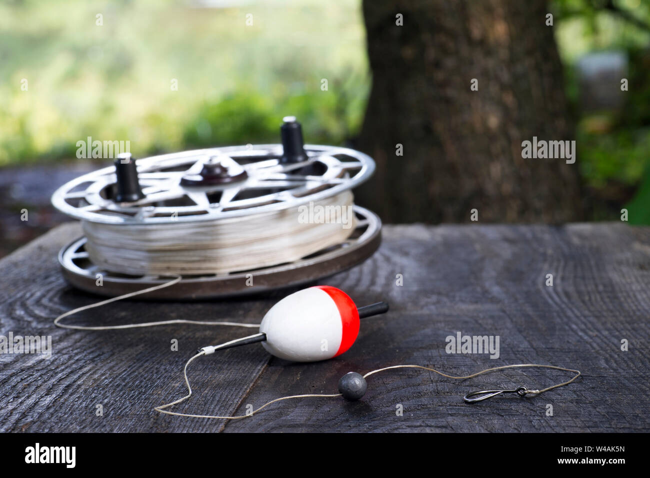 Fishing reel with fishing line, red and white float, hook and sinker on  wooden table on natural background. The concept of classic fishing tackle.  Tex Stock Photo - Alamy