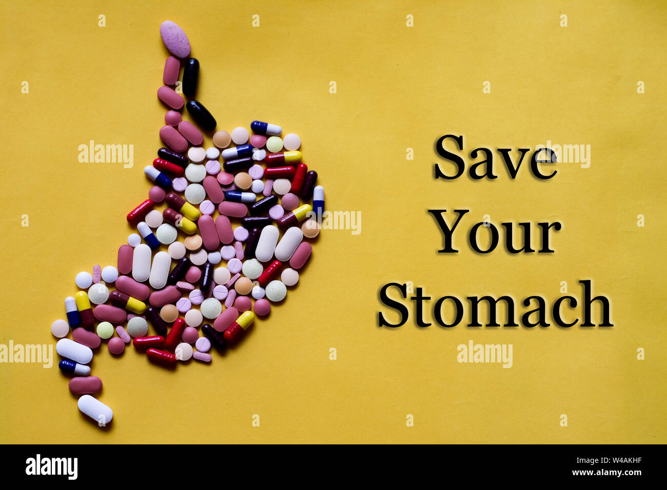 Medicine pills tablets capsules in shape of human stomach in yellow