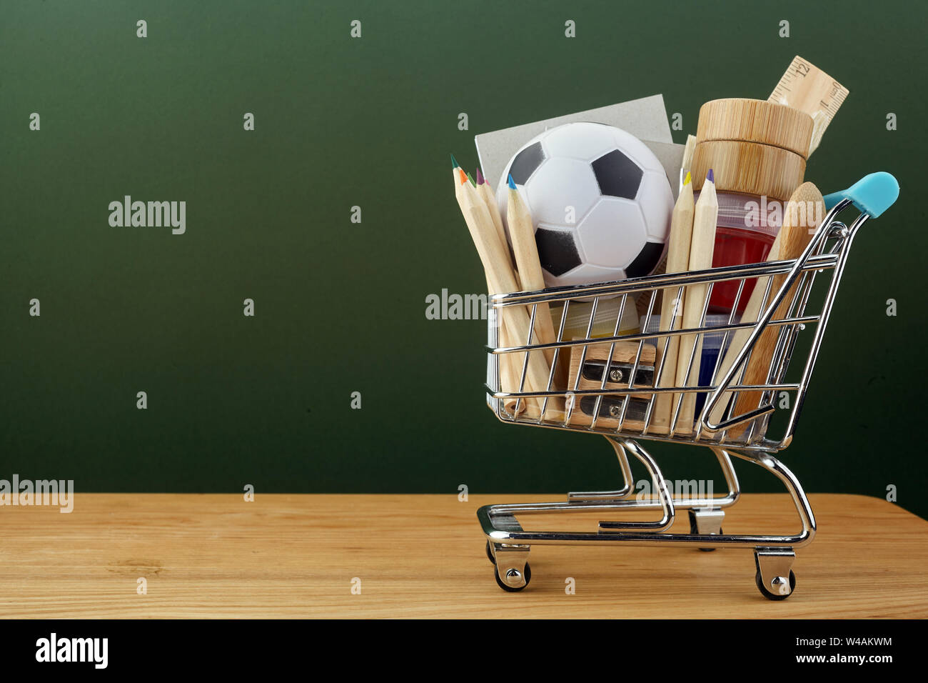 Shopping cart with school supplies over chalkboard background. Back to