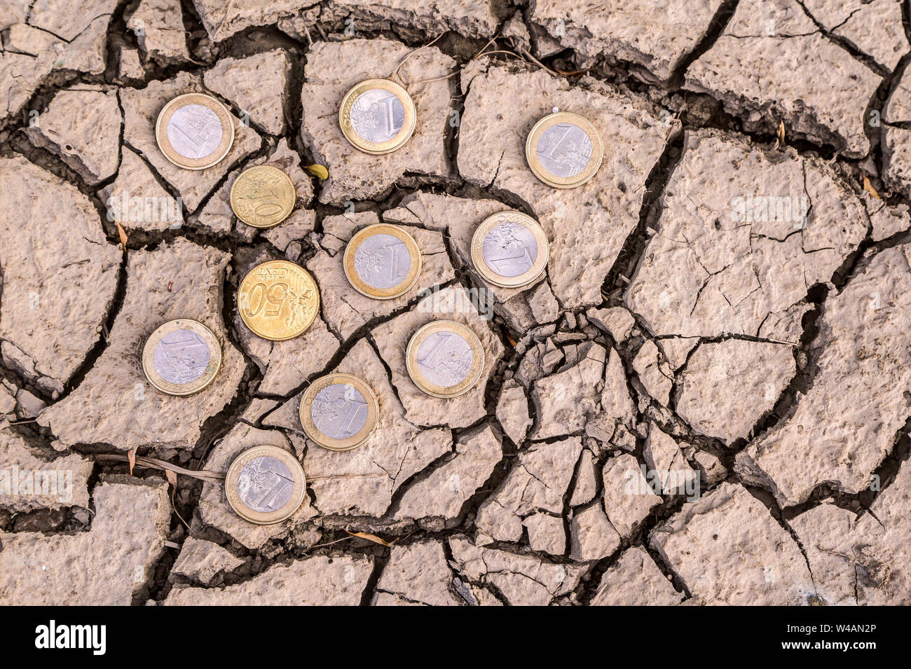 Euro coins on dry ground.. How much does climate change cost? Climate change leads to extreme weather events which cause considerable economic damage. Stock Photo