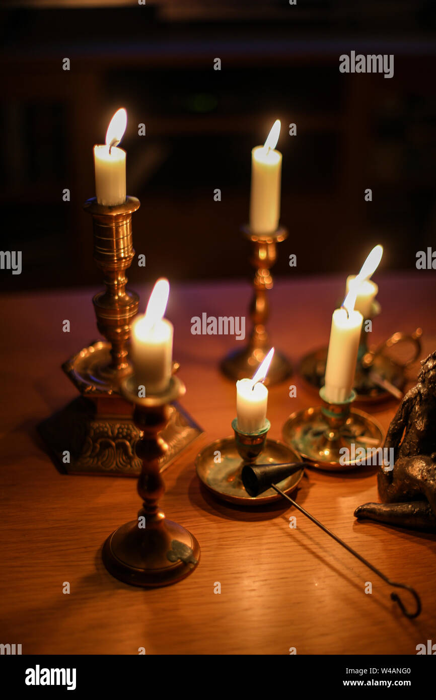 Burning candles in old brass candle holders Stock Photo