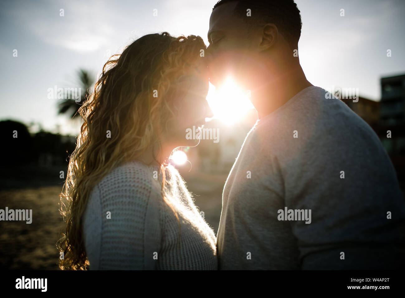Multi racial couple embrace on beach at sunset Stock Photo - Alamy