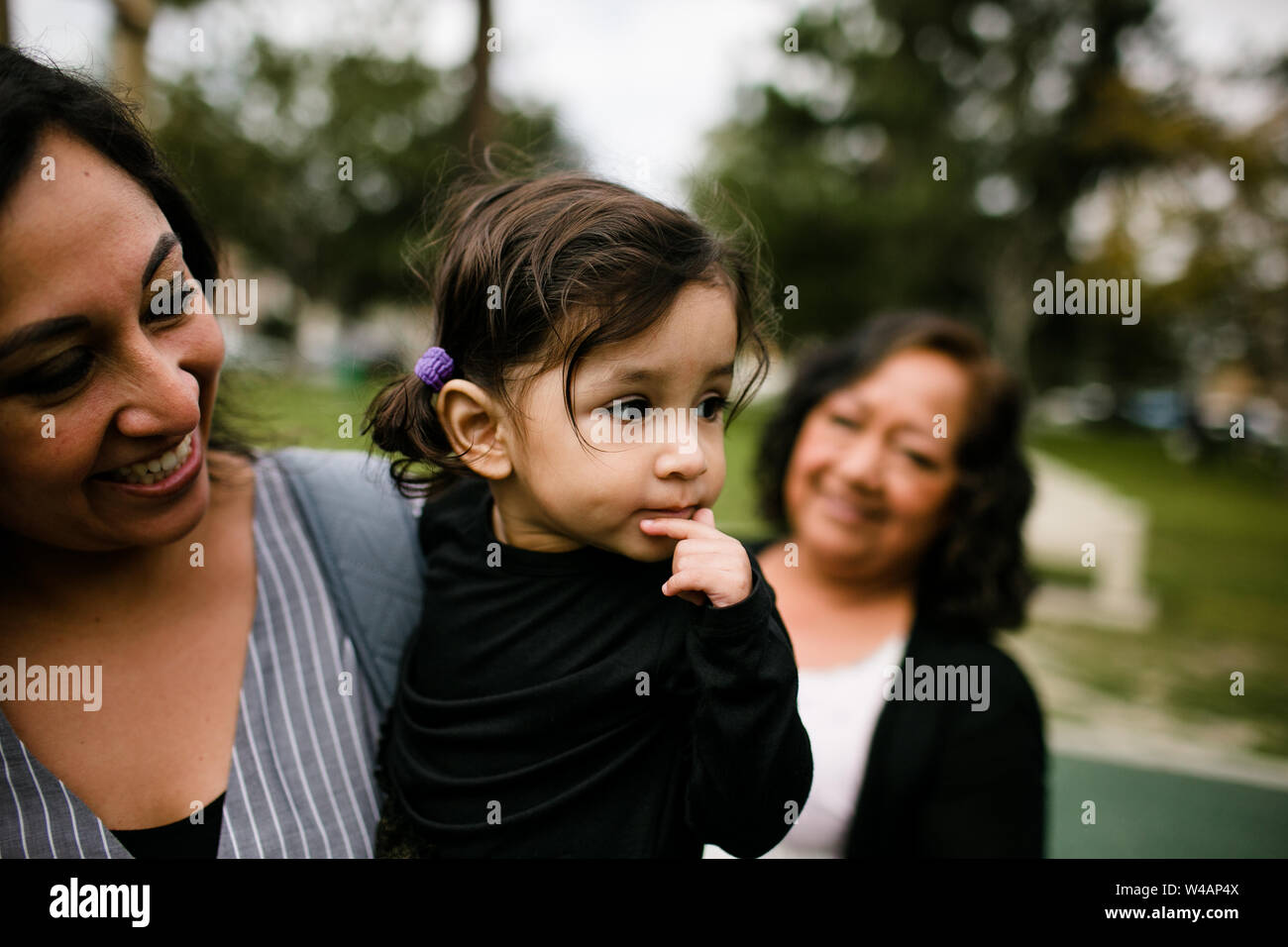 Mother holding daughter as grandmother looks on Stock Photo