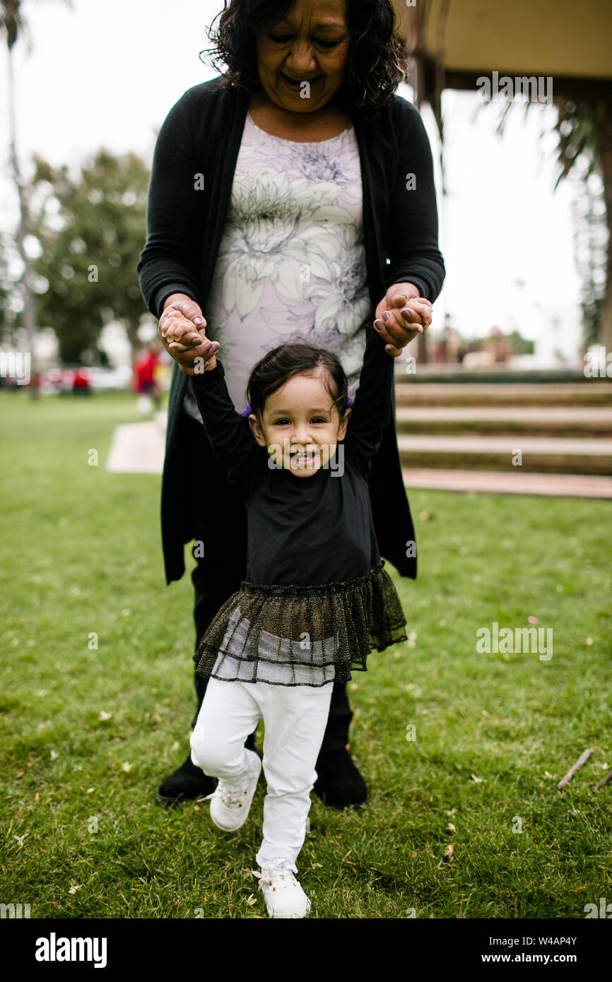 Grandmother holding granddaughter's hands while standing and laughing Stock Photo