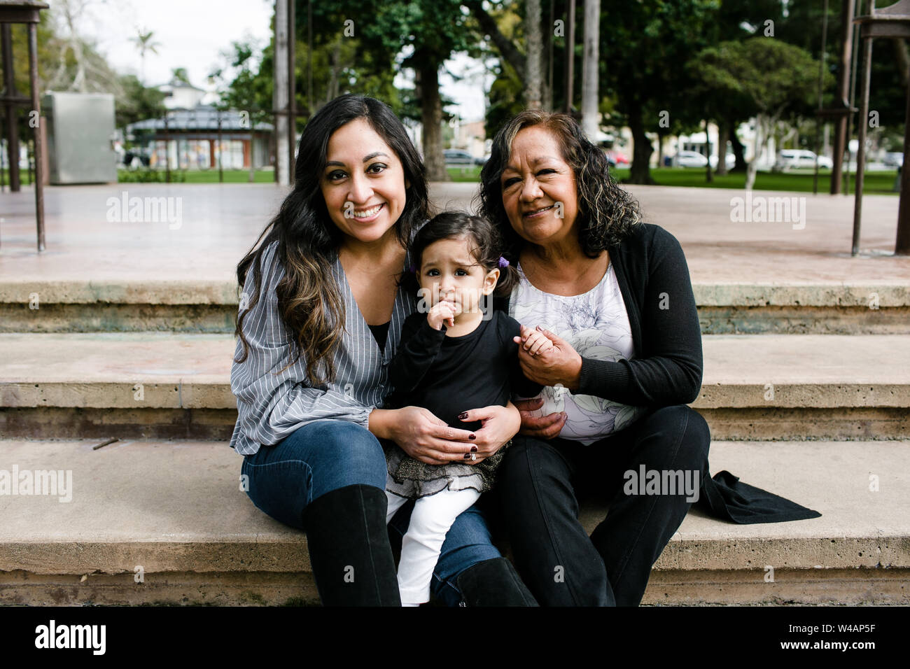 Three generations of women smiling for camera in park Stock Photo
