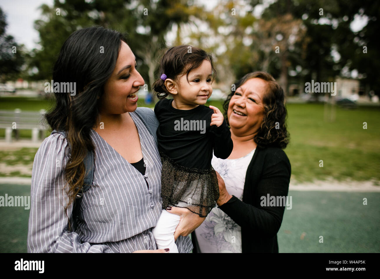 Mother holding daughter as grandmother looks on Stock Photo