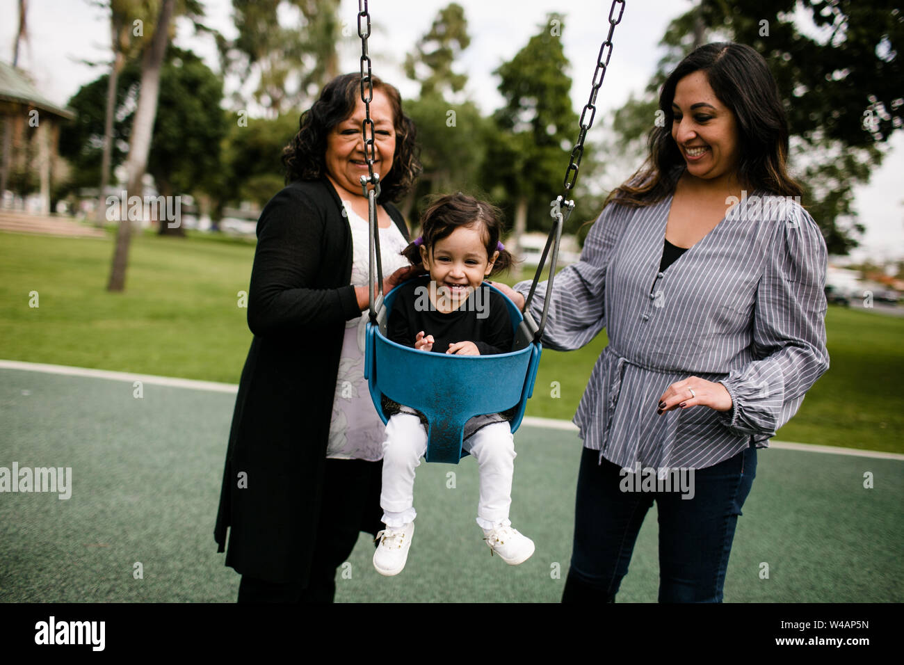 Grandmother and mother pushing laughing little girl Stock Photo