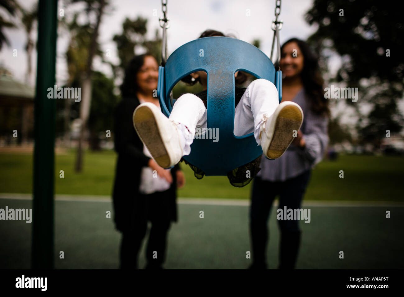 Little girls feet in air as she swings at playground Stock Photo